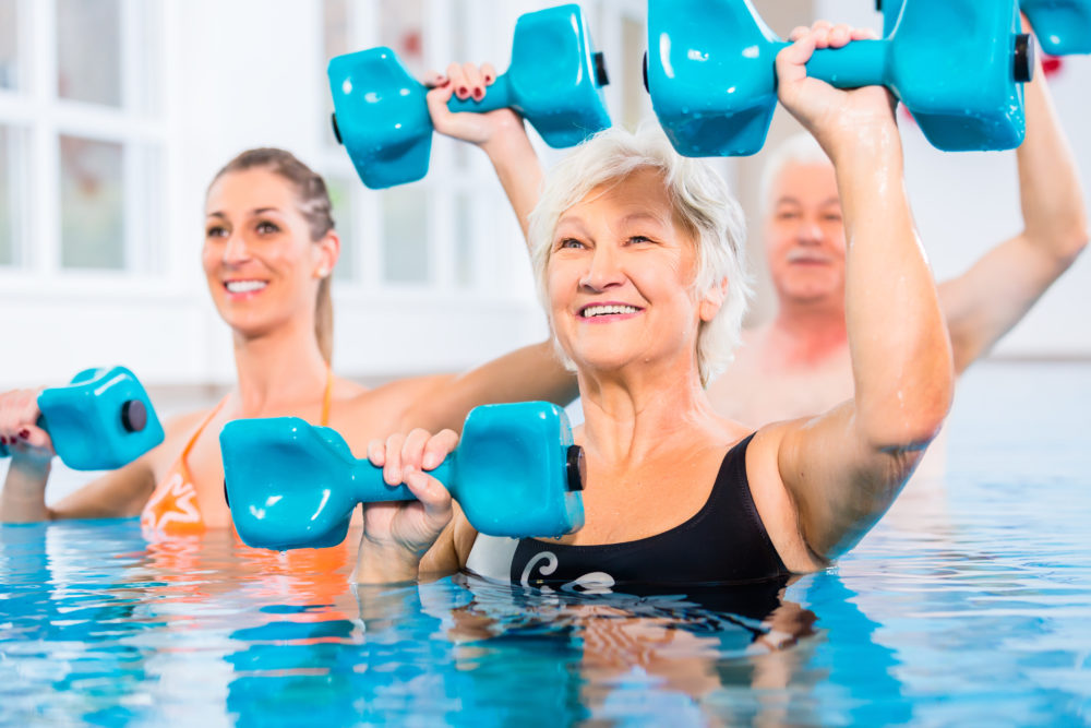 Young and senior people doing aquatic exercise in pool